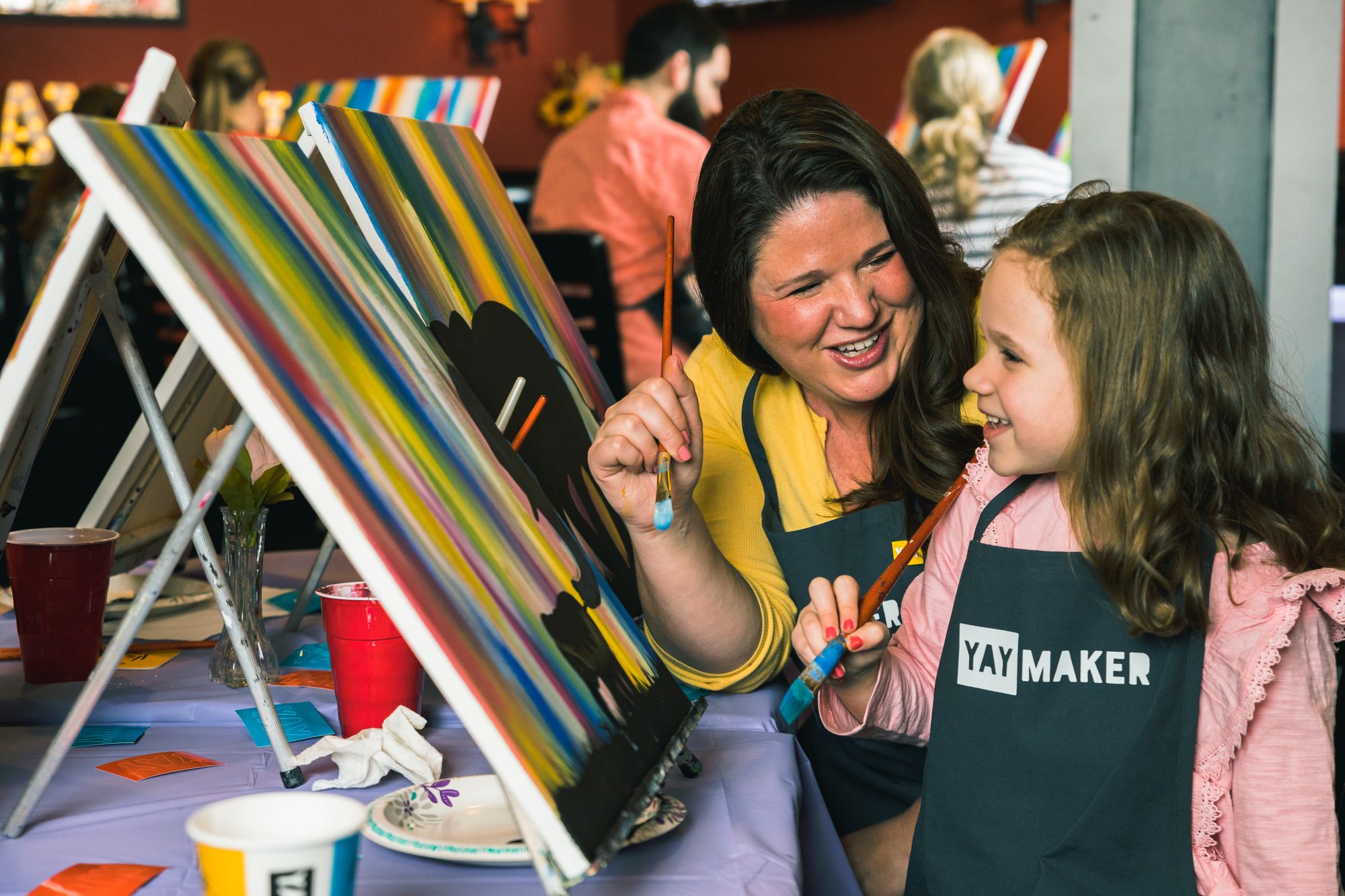 Mother and daughter smiling at a Mother's Day Paint Nite