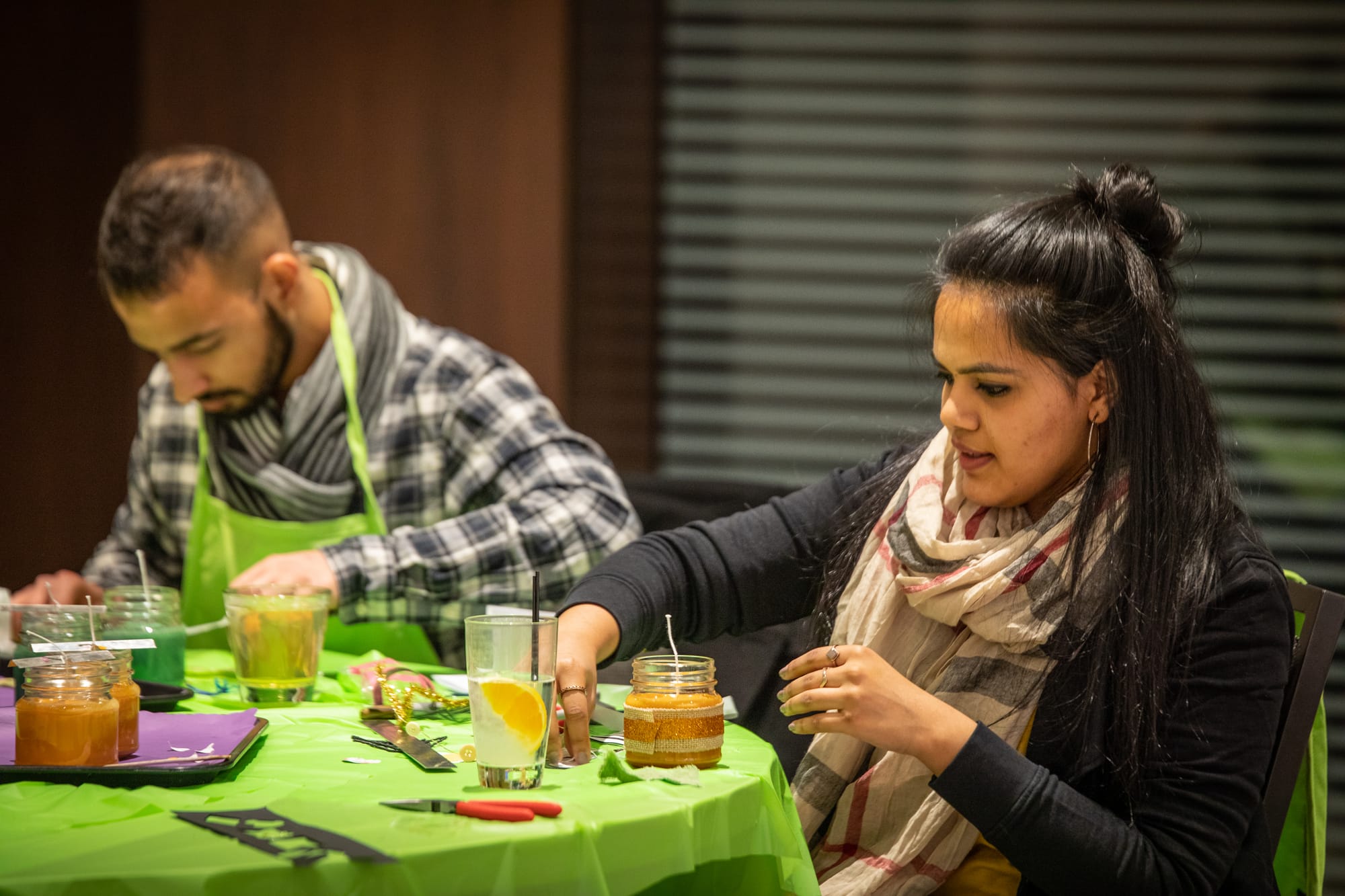 Couple participating in candle making class at a restaurant's private event space, working with wax and supplies