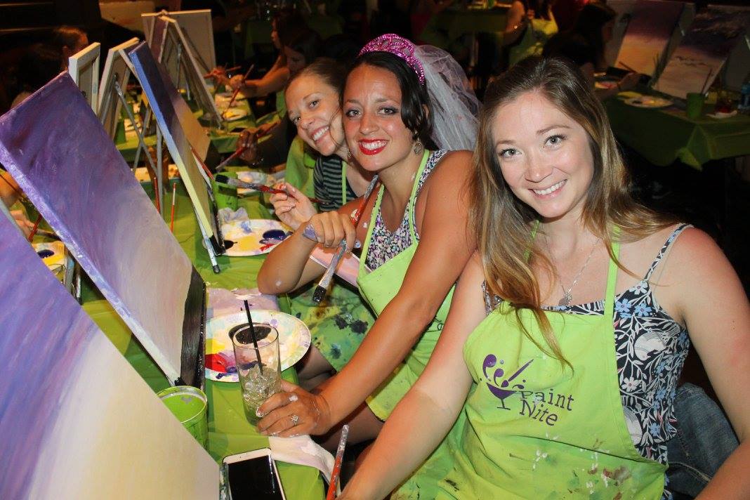 Women painting at bachelorette paint and sip party with drinks