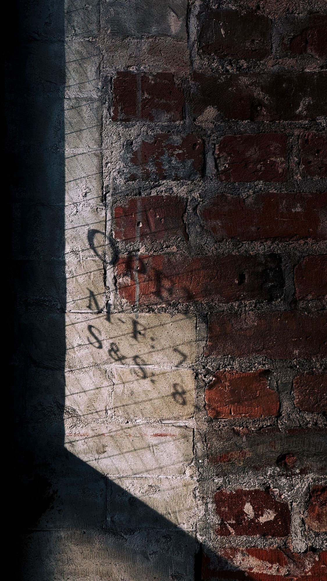 Shadow on brick of Gasoline Alley’s open hours printed on their entrance door, from reflecting sunlight.