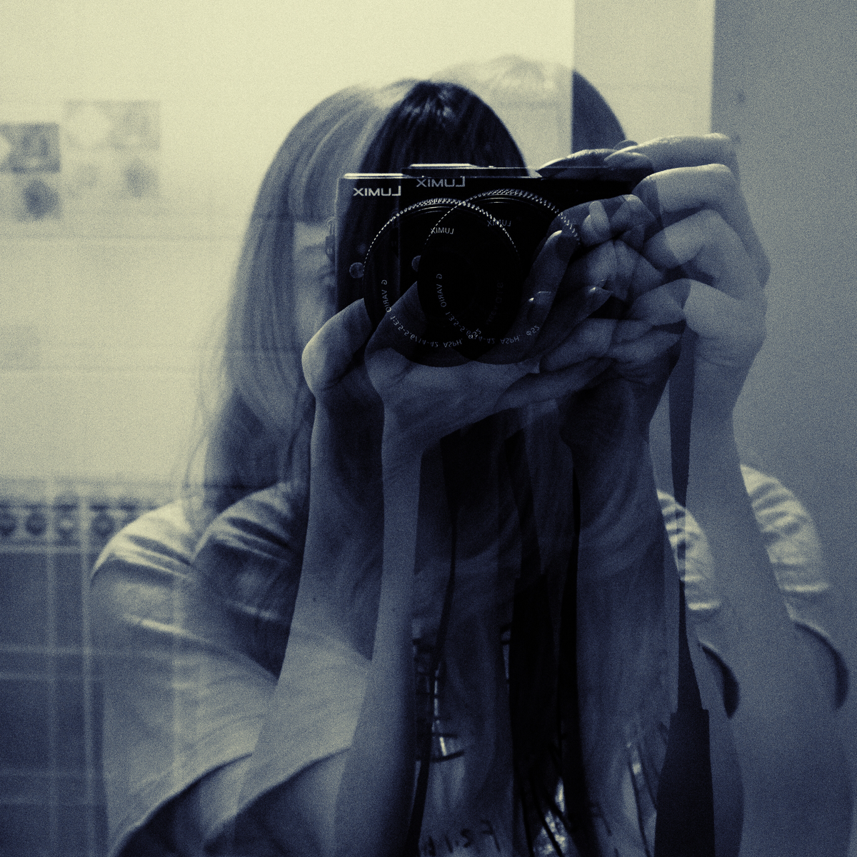 blurred photo (depicting movement) of a woman taking her photo as reflected by a mirror