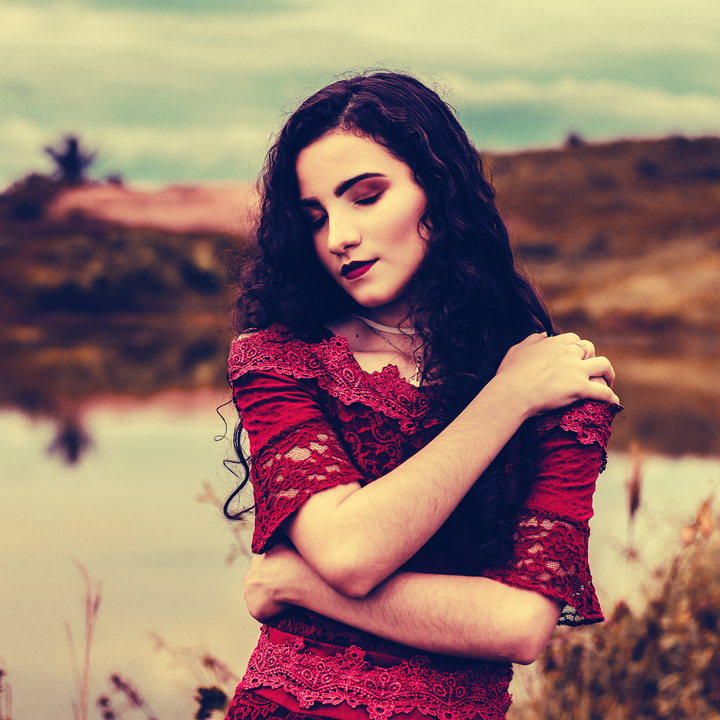 woman hugging herself, wearing a crimson lace dress 