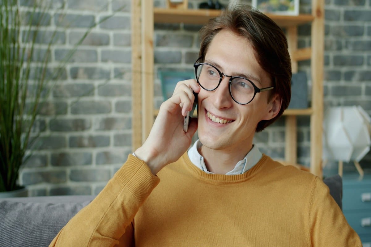 Uomo seduto che parla al cellulare con tono calmo e attento, simbolo di comunicazione consapevole e rispetto dei confini nel contatto