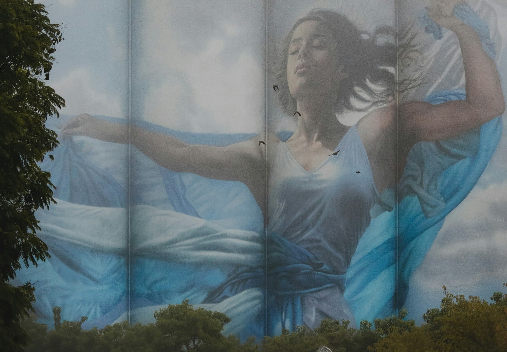Mural of a dancing woman above two abstract human sculptures.