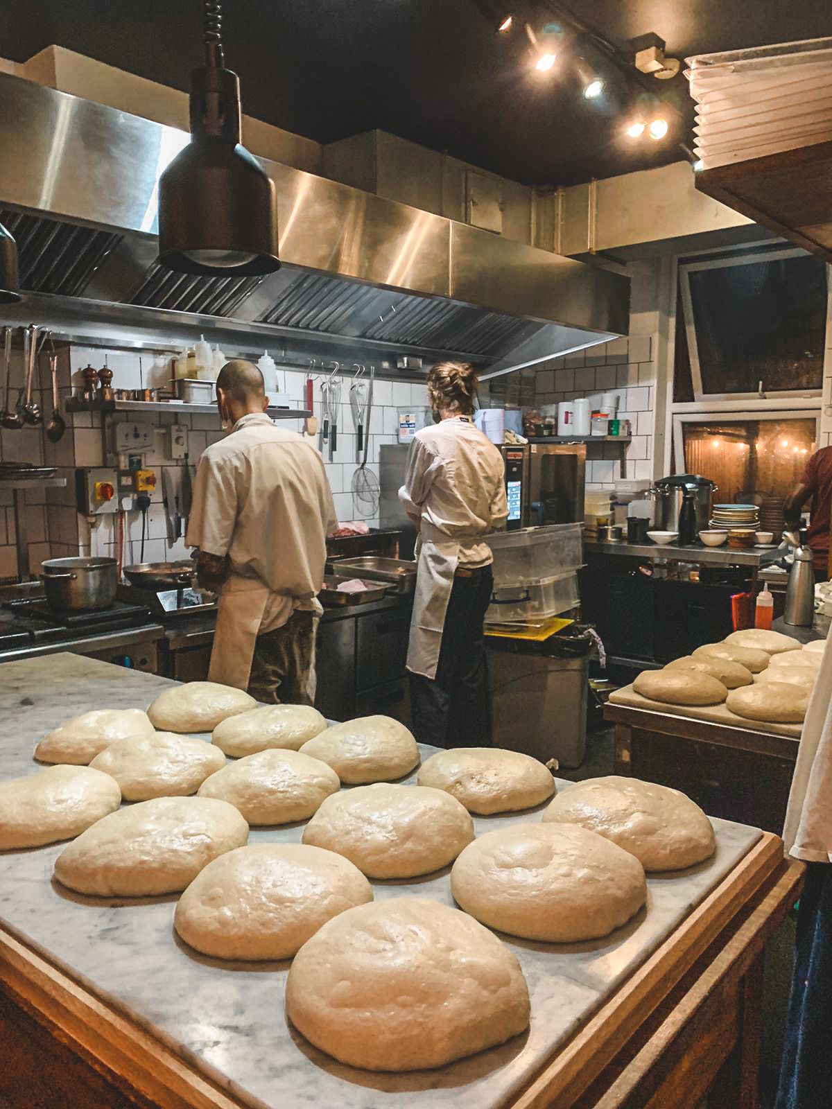 Casa Fofo's open kitchen with rounds of dough rising on a marble countertop, ready for the oven.