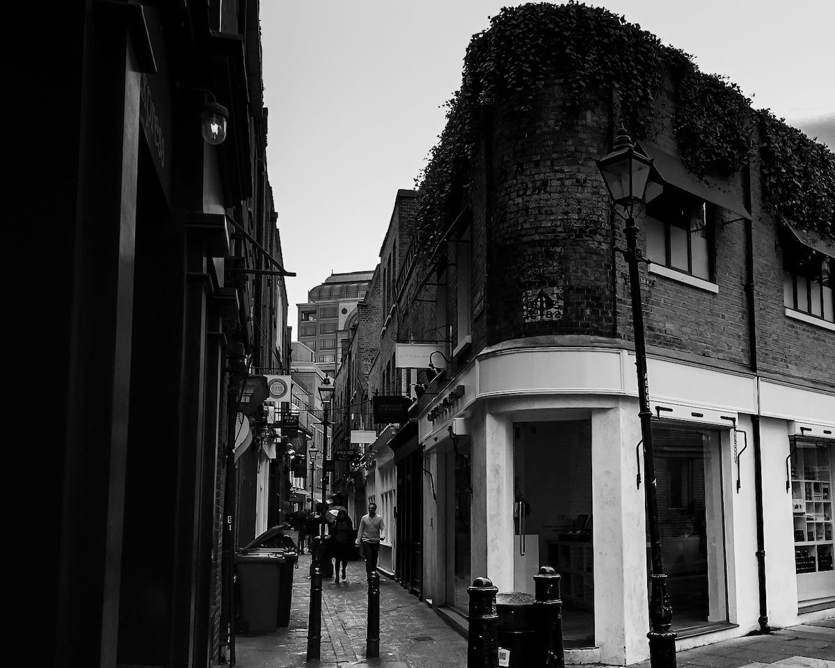 A quiet, atmospheric alley in Whitechapel with historic brick buildings and vintage street lamps.