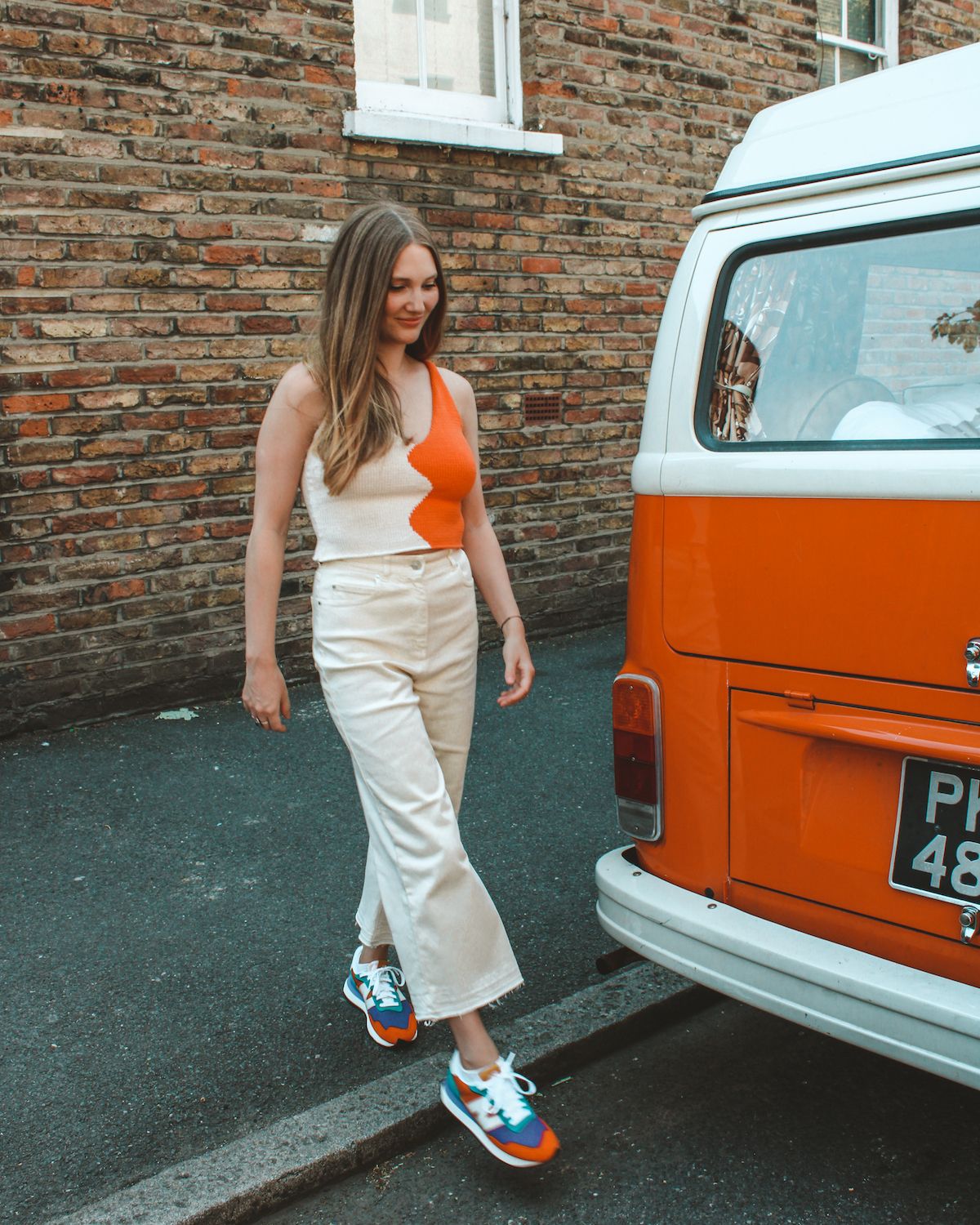 Cec walks past a vintage orange-and-white van on a East London street.