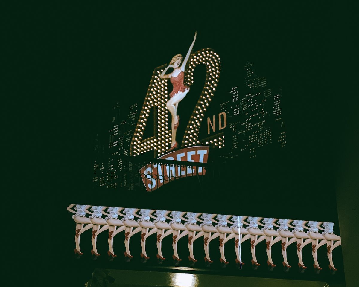A lit-up marquee sign featuring a line of dancers advertising the musical "42nd Street."