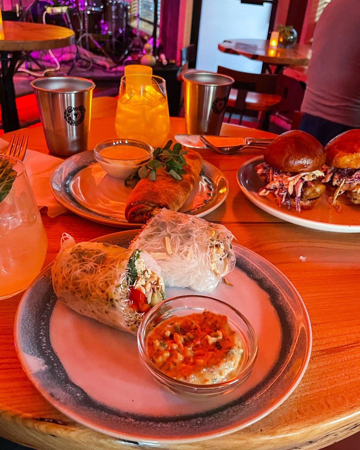 Fresh spring rolls and sliders served at Mateada, with vibrant stage lights in the background.