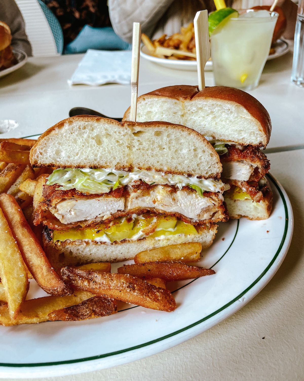 Crispy chicken sandwich with pickles and fries on a white plate, served at Cassette restaurant on Salt Spring Island.