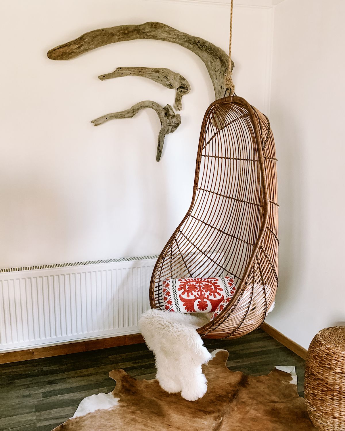  Cozy indoor corner with a rattan hanging chair, a sheepskin rug, and driftwood decor on the wall at Toore Patagonia.