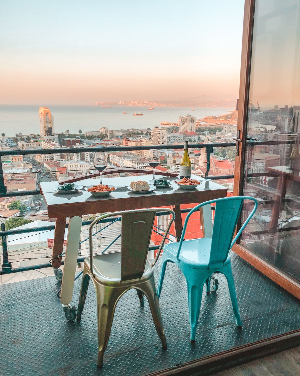 Rooftop dinner on a private balcony at Hotel Winebox with ocean views, two glasses of wine, and plates of pasta at sunset.