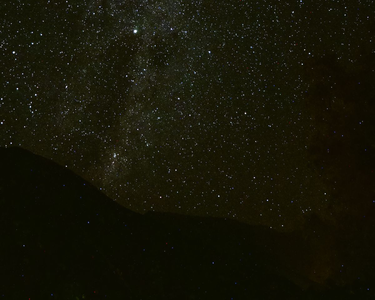 Starry night sky over Chile, with a silhouette of dark mountains beneath a sparkling Milky Way.