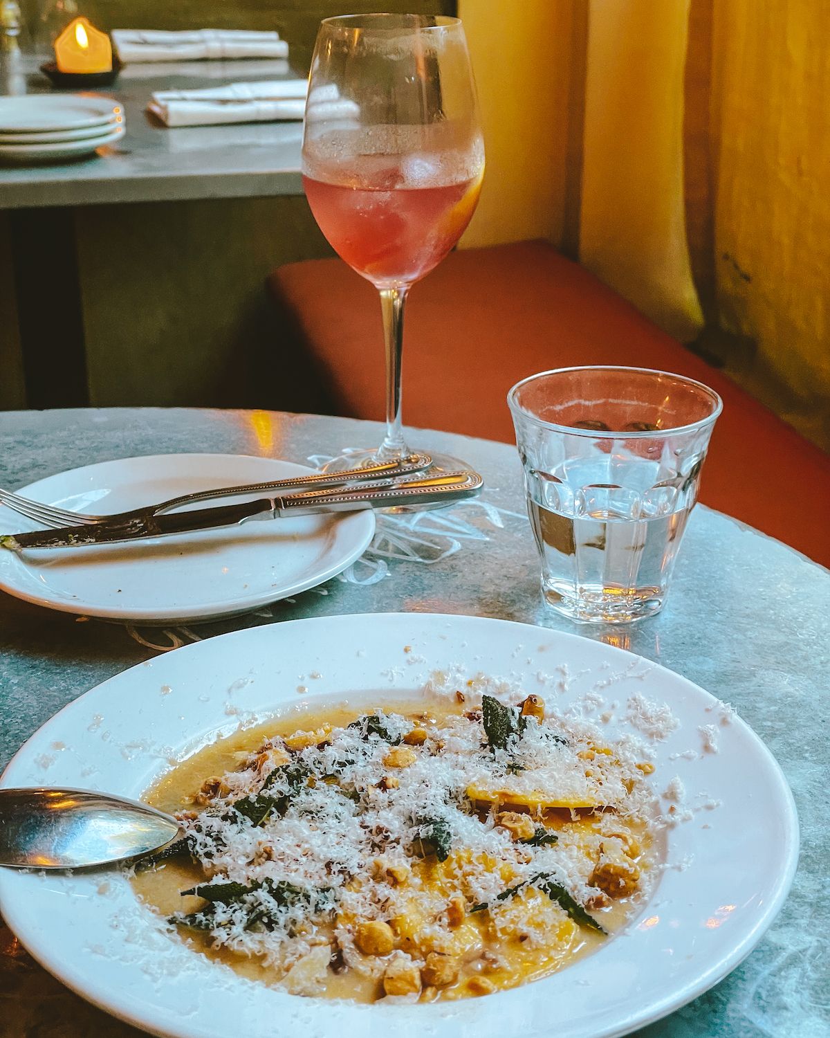 A plate of pasta topped with cheese and crispy sage, paired with a glass of rosé at Jolene.