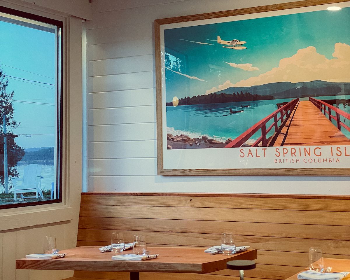 Interior view of Off The Hook featuring a vibrant “Salt Spring Island, British Columbia” poster above wooden seating
