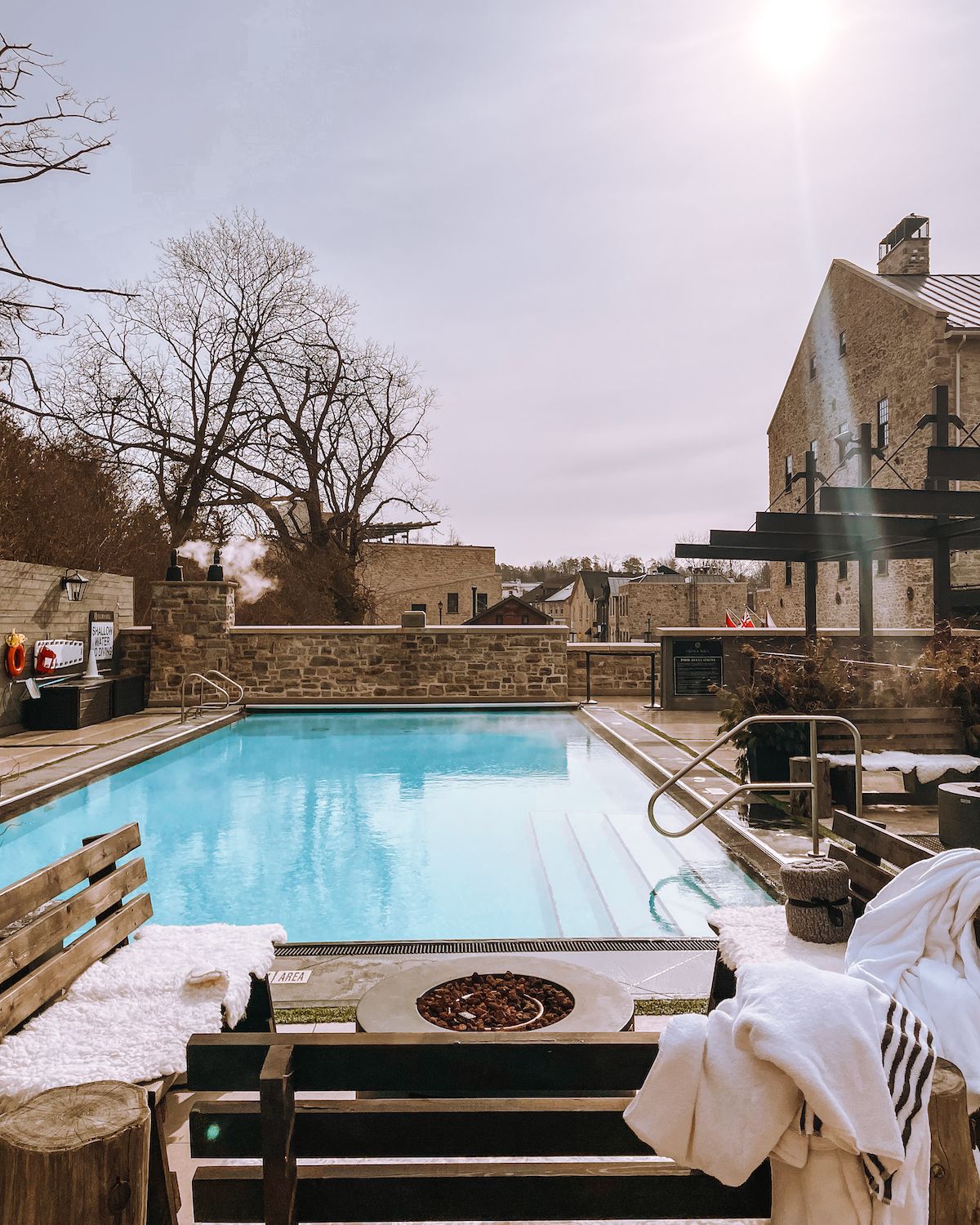 Heated outdoor pool with fire pit on a chilly winter's day at Elora Mill Hotel & Spa 