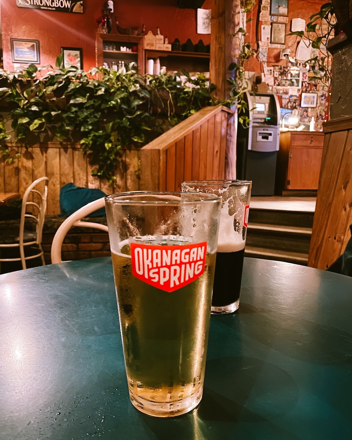 Two Okanagan Spring beers on a green table inside the rustic Hummingbird Pub.