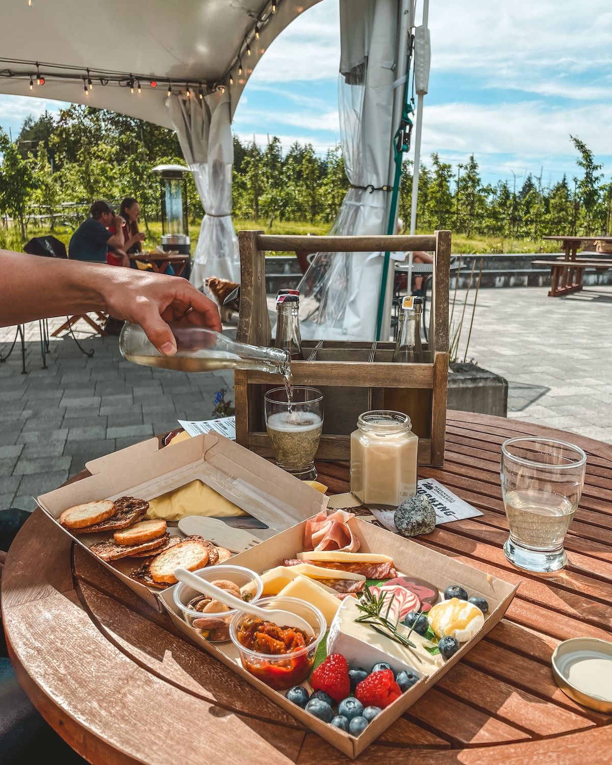 Charcuterie box and cider pouring into a glass on the outdoor terrace of Ravenskill Orchards