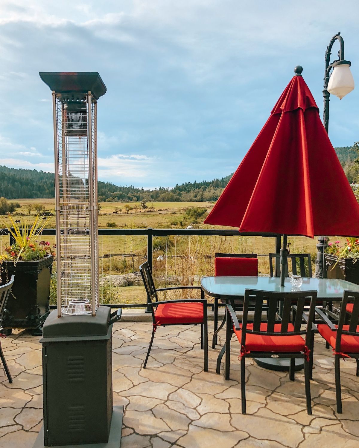 Patio with red chairs overlooking a pasture and hills, offering serene island dining.