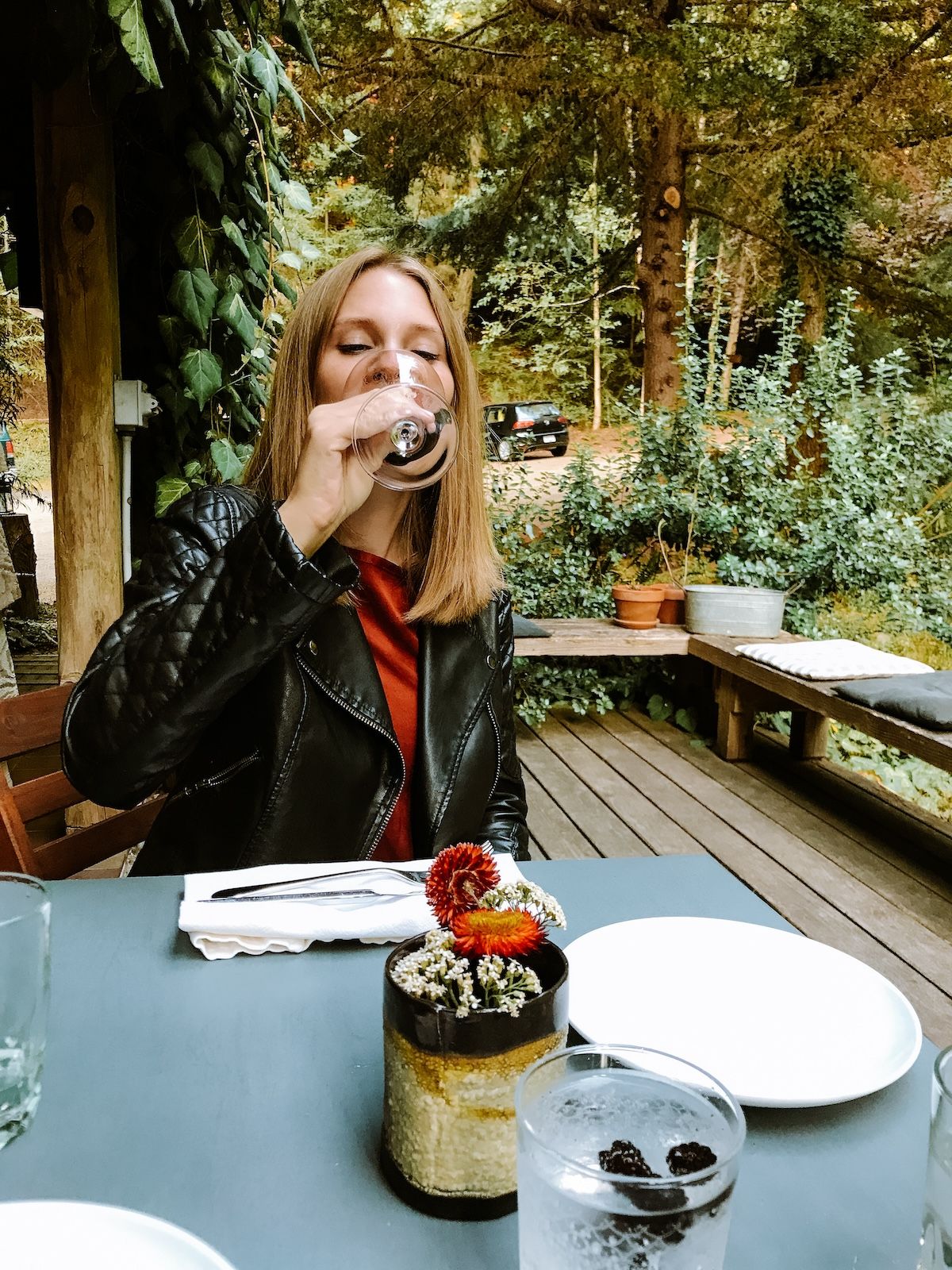 Cec sipping wine on a deck surrounded by lush greenery at Pilgrimme.