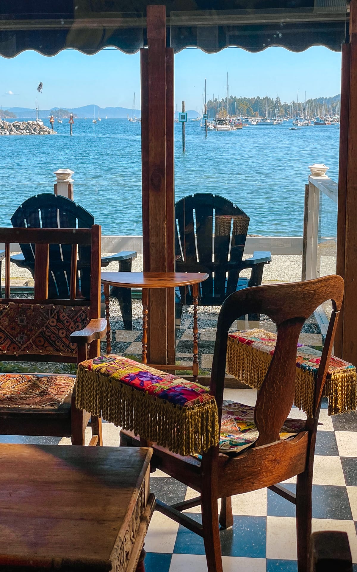 Cafe interior at Waterfront Country Cafe with eclectic seating and ocean views through large windows.