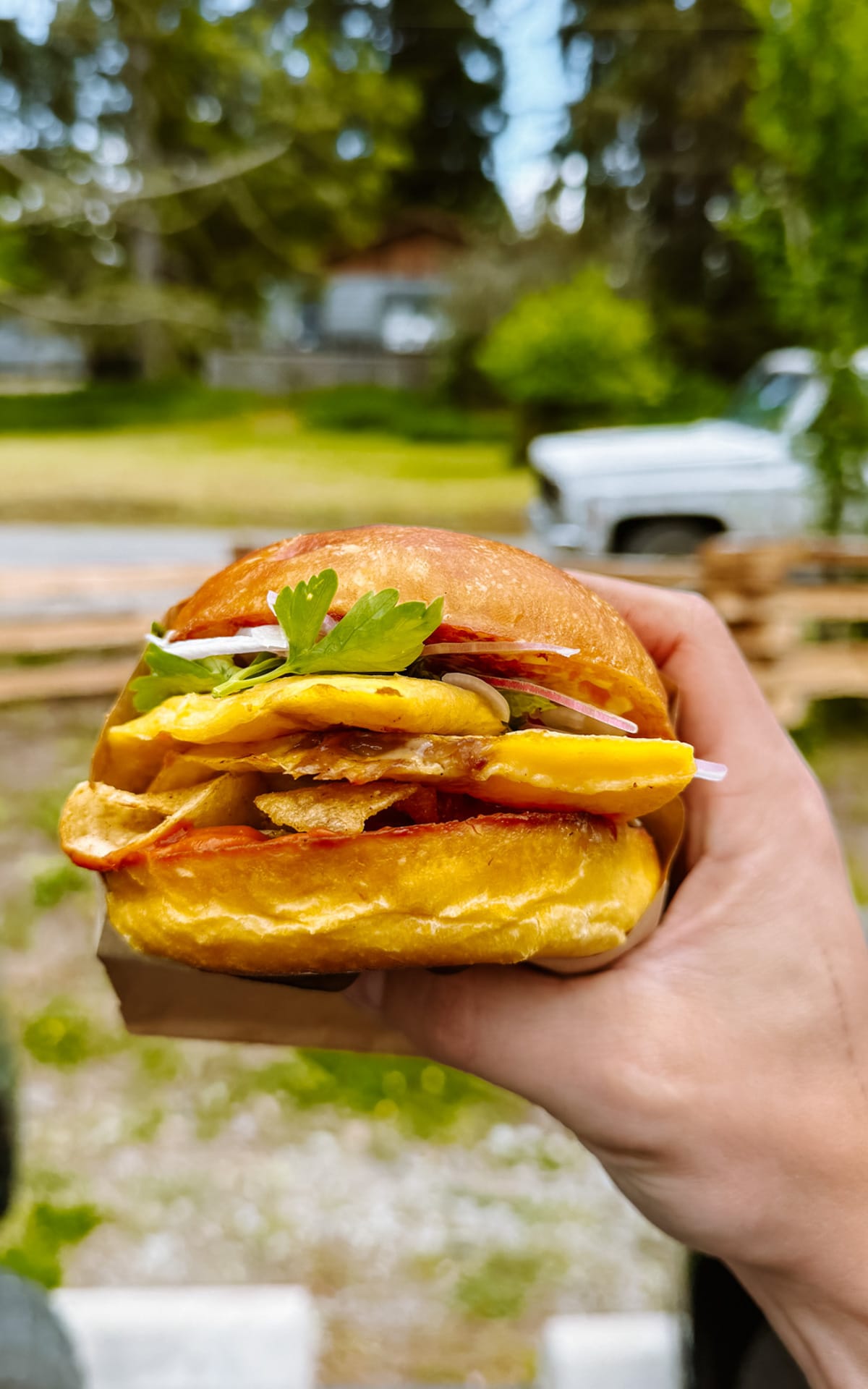 Breakfast sandwich from Francis Bread on Salt Spring Island, stacked with egg, crispy chips, greens, and served on a potato bun.