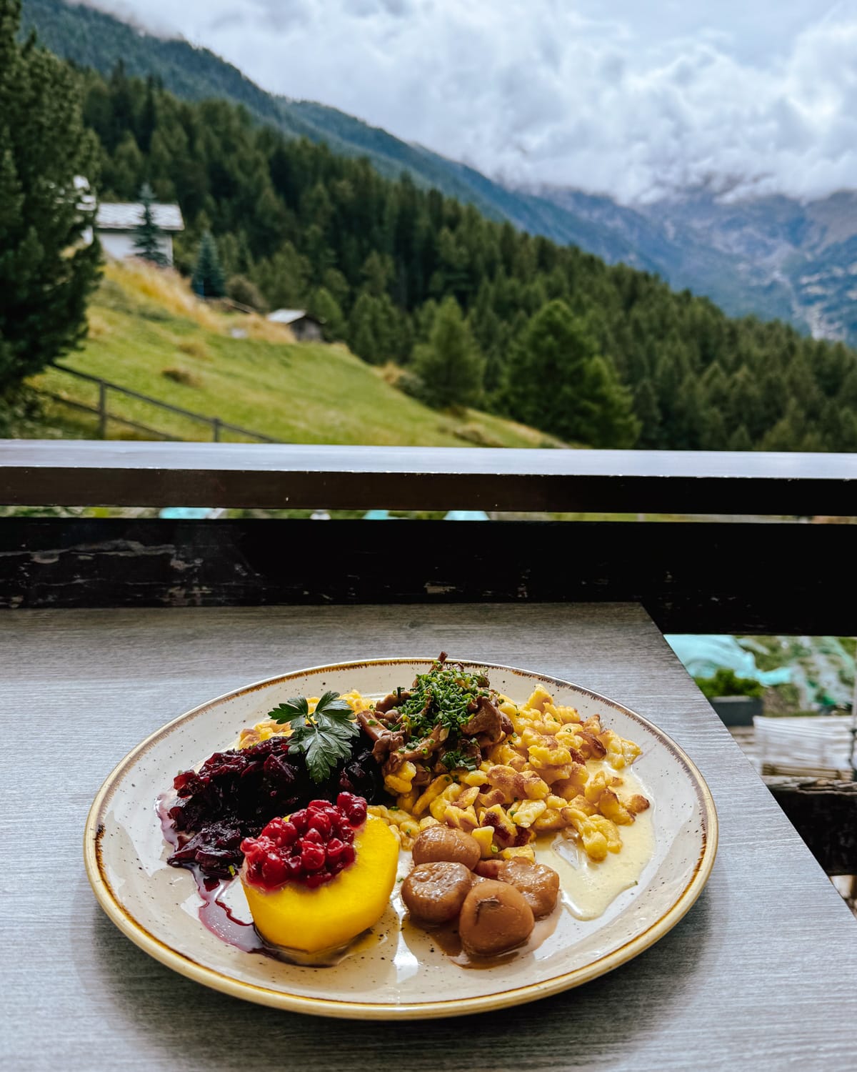 Plate of Swiss cuisine, including rösti and lingonberries, overlooking Alpine meadows and misty mountains at Restaurant Ried.