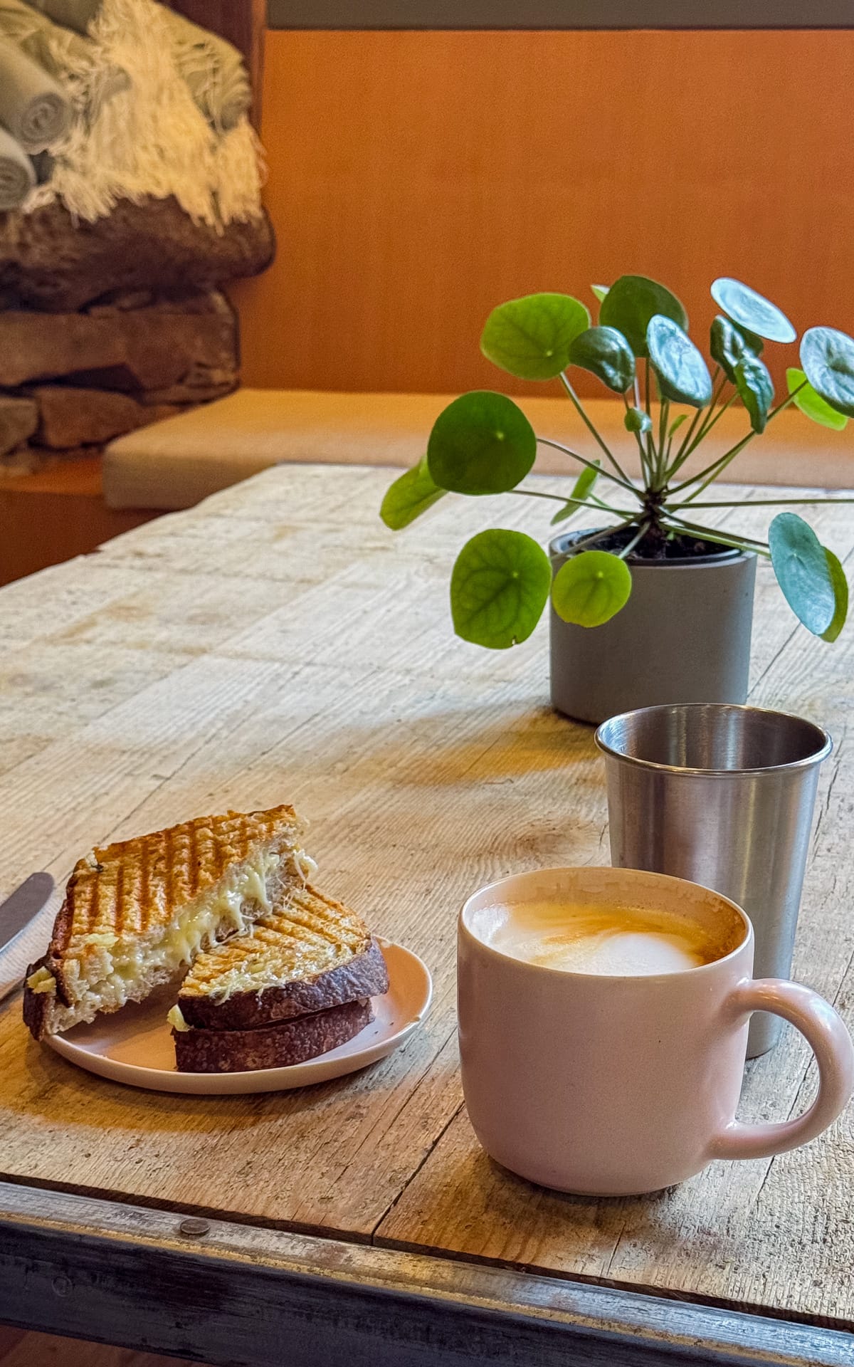 Rustic cafe table with a latte and grilled cheese sandwich.