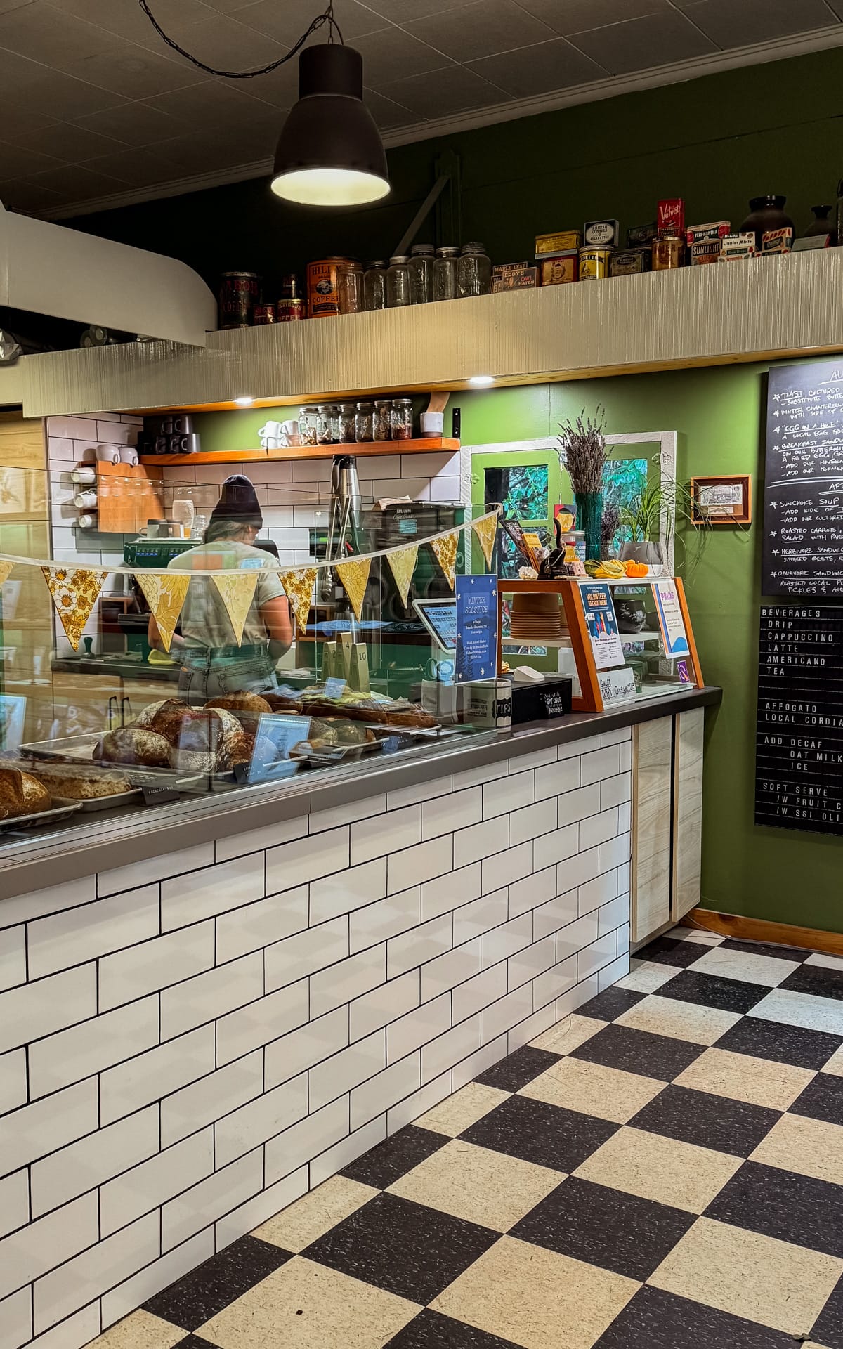 Cafe counter with fresh bread, pastries and a black and white tile floor.
