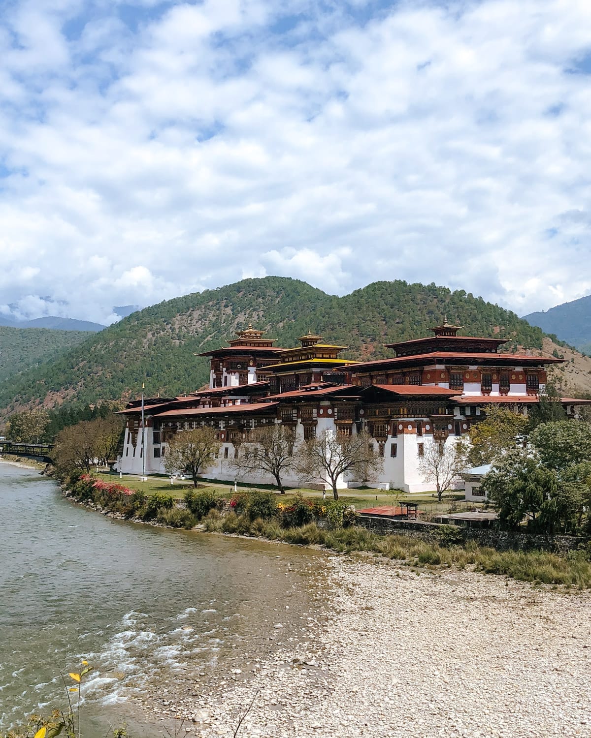 Punakha Dzong, a majestic Bhutanese fortress, standing at a river surrounded by green mountains.