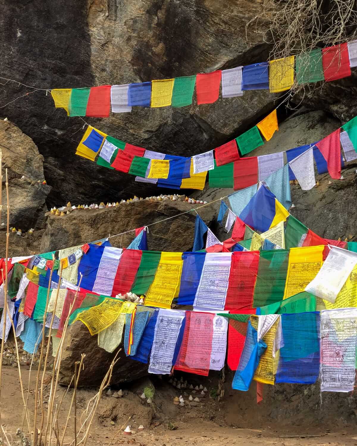 Colorful prayer flags in Bhutan hanging against a rocky backdrop, inscribed with prayers and mantras fluttering in the wind.