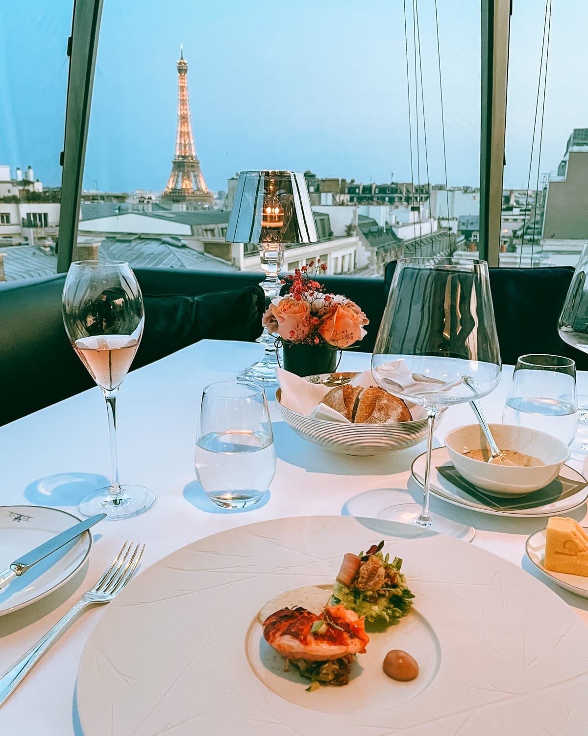 Fine dining at a rooftop restaurant in Paris with a glowing Eiffel Tower view. 