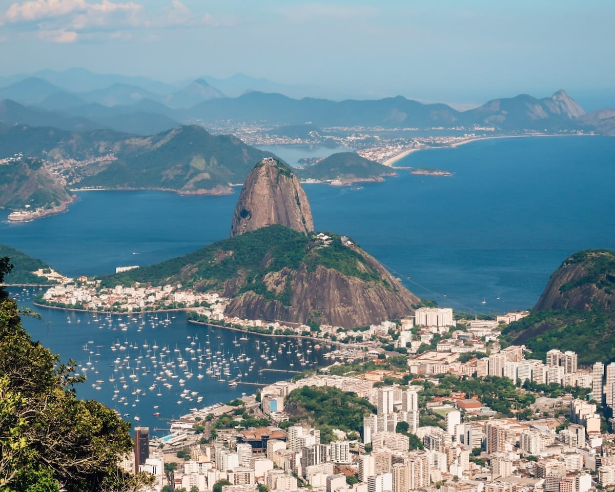 Sugarloaf Mountain rises above the Rio de Janeiro coastline, with sailboats in the bay and the city stretching below.
