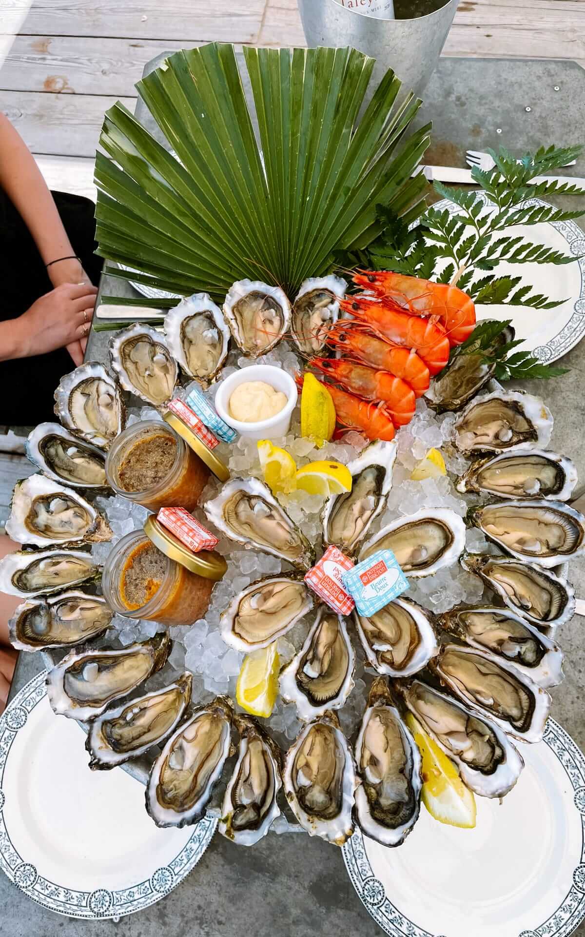 A seafood platter featuring fresh oysters, shrimp, pâté, and lemon wedges, elegantly arranged on a bed of ice.