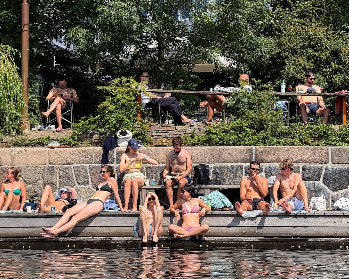Locals sunbathing and hanging out by the canal at La Banchina, a favourite summer hangout in Copenhagen.
