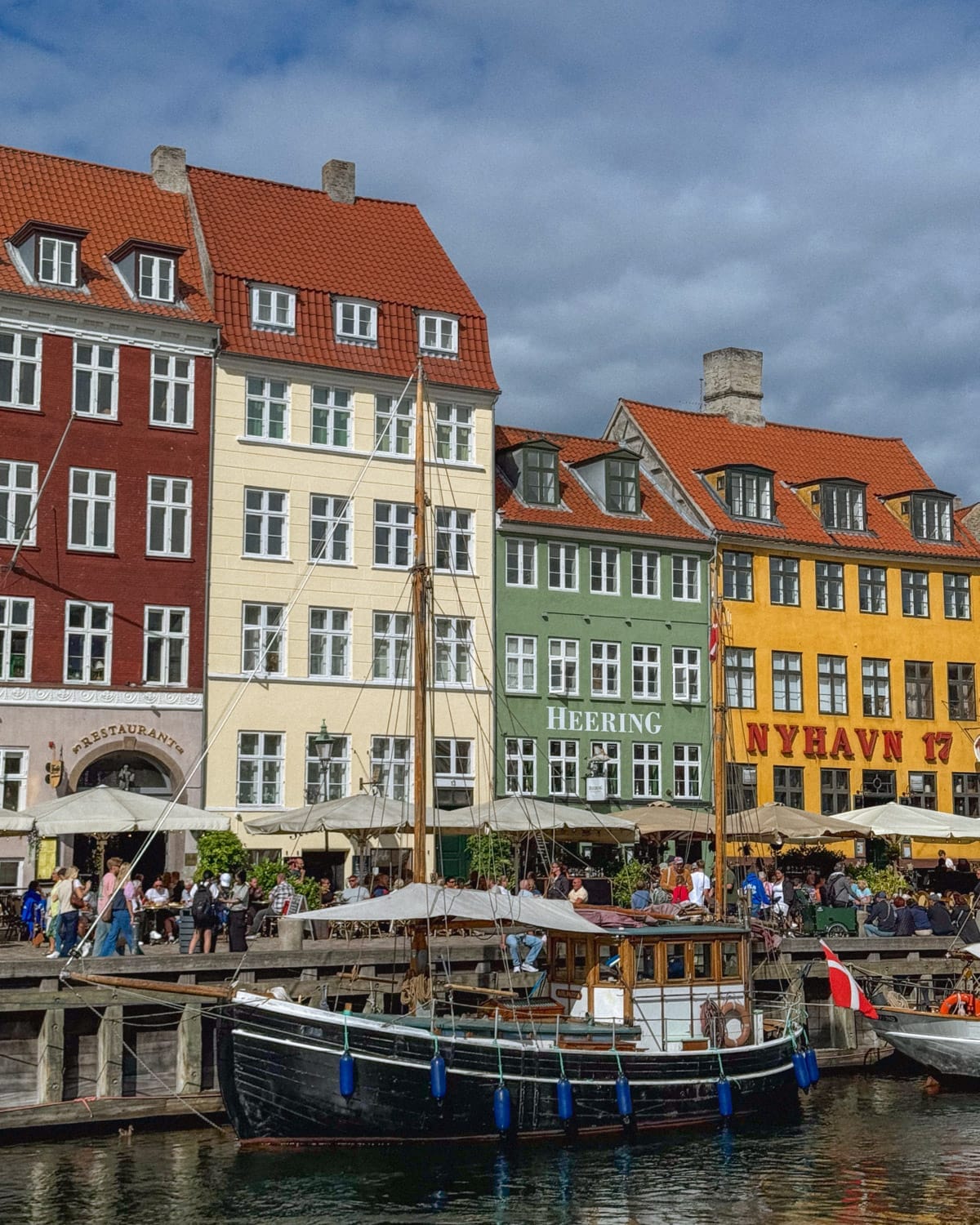 Colourful buildings along the Nyhavn canal in Copenhagen with boats docked in front.