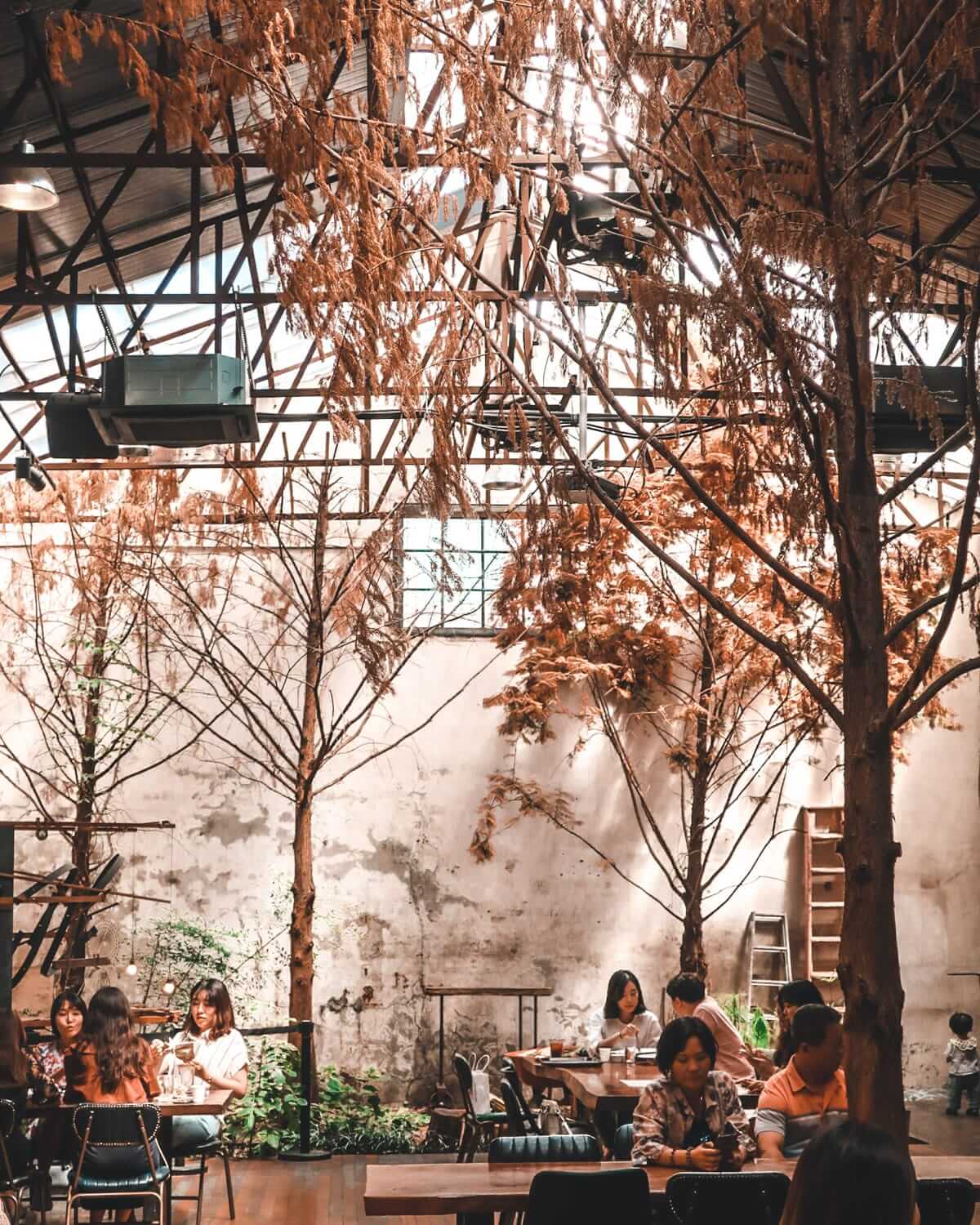 An alternative cafe with dried trees and warm lighting in Seoul, blending industrial design with nature-inspired decor.