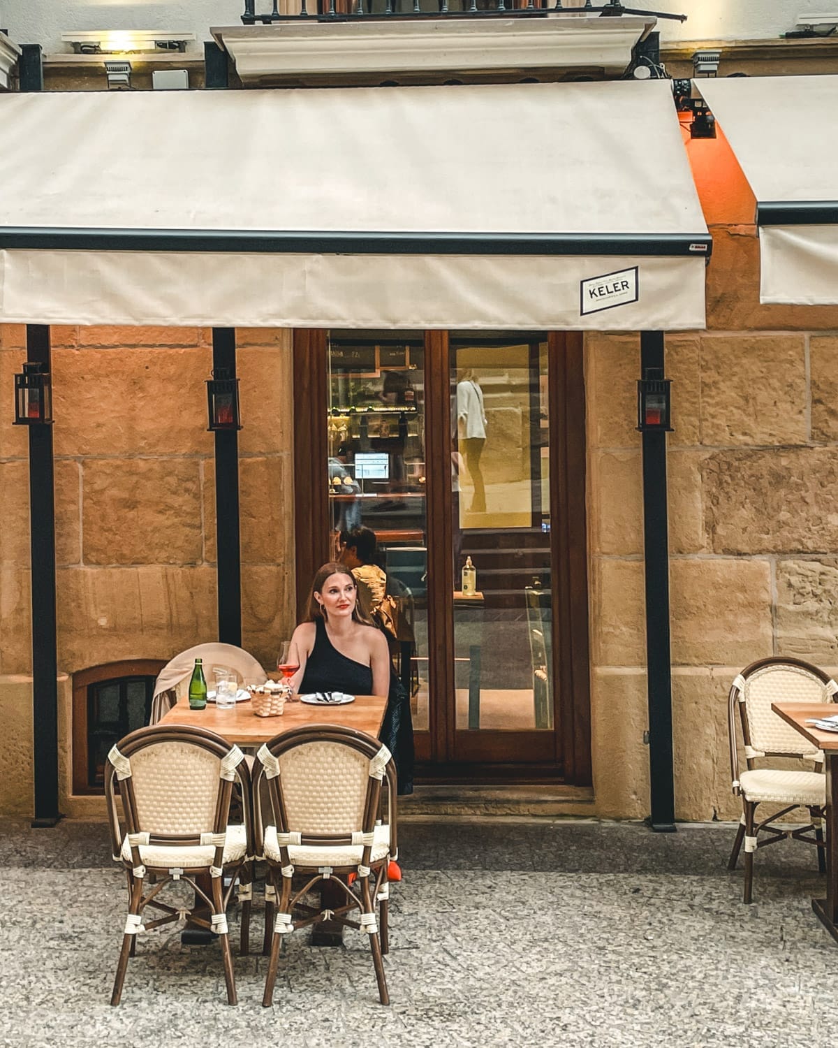 Cec dining outside a San Sebastián restaurant with classic bistro chairs and awning.
