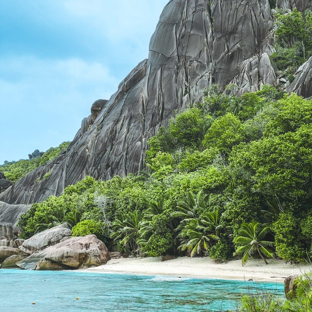 Secluded beach with soft sand, turquoise water, and dramatic granite cliffs at Anse Marron in the Seychelles.