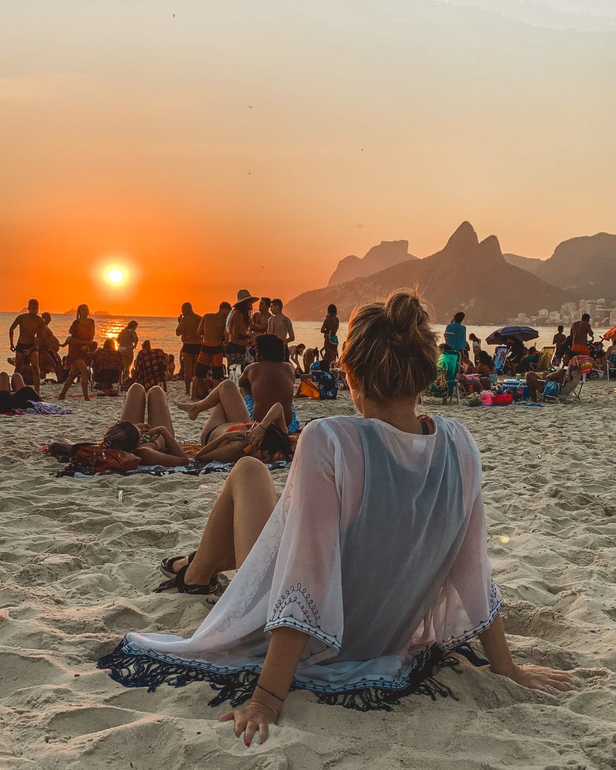 A crowd gathers on Ipanema Beach in Rio de Janeiro to watch the sunset, capturing Brazil’s vibrant beach culture.