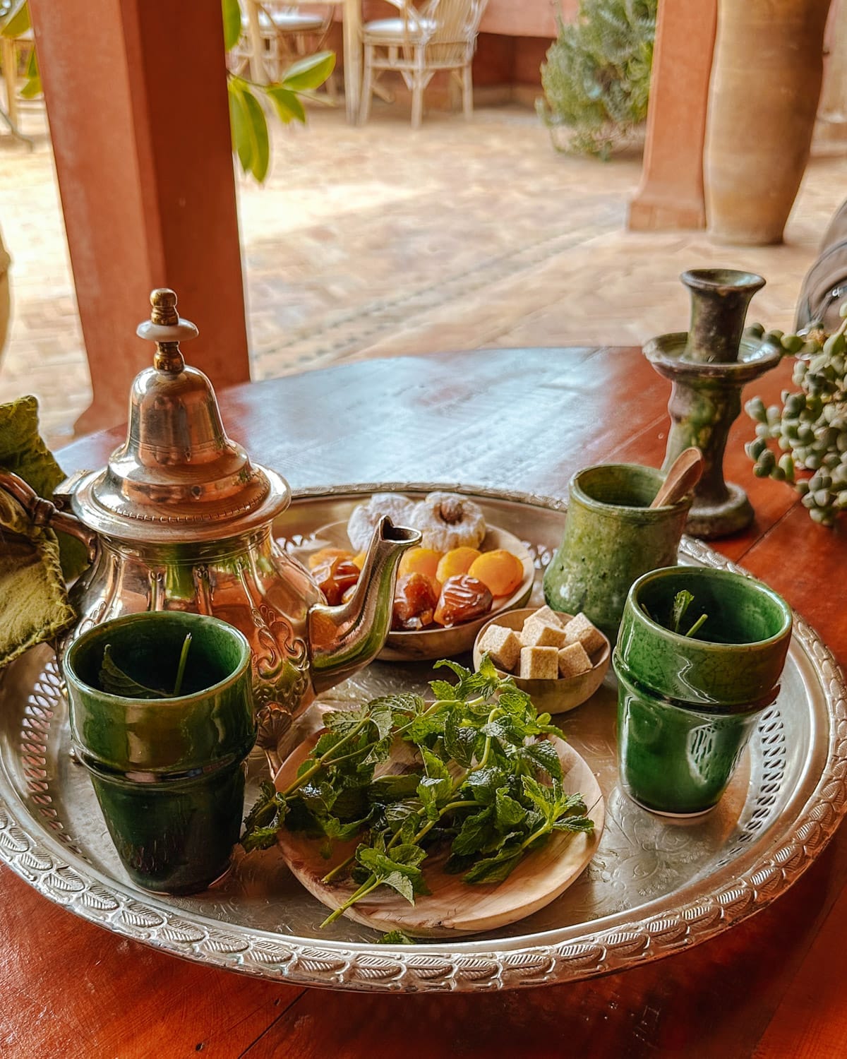 Traditional Moroccan tea service with mint tea, sugar cubes, and dried fruit on a silver tray.