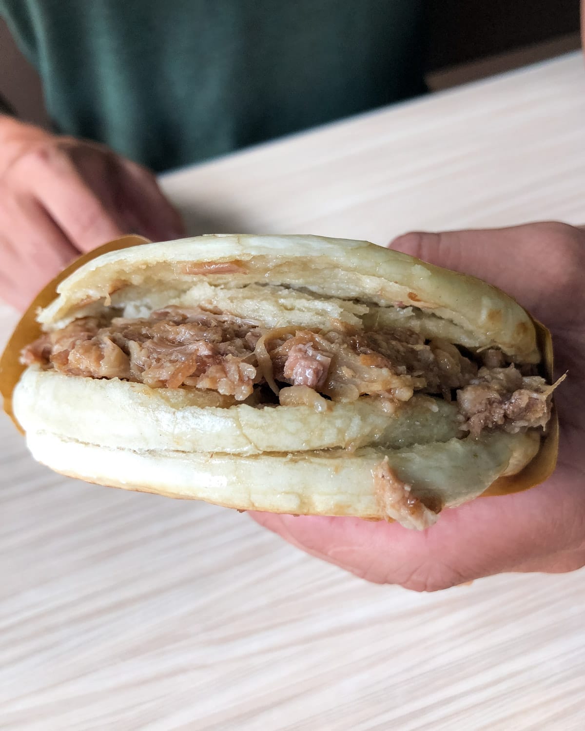 Close-up of a juicy roujiamo, China’s meaty street food sandwich, filled with shredded pork inside crispy flatbread.