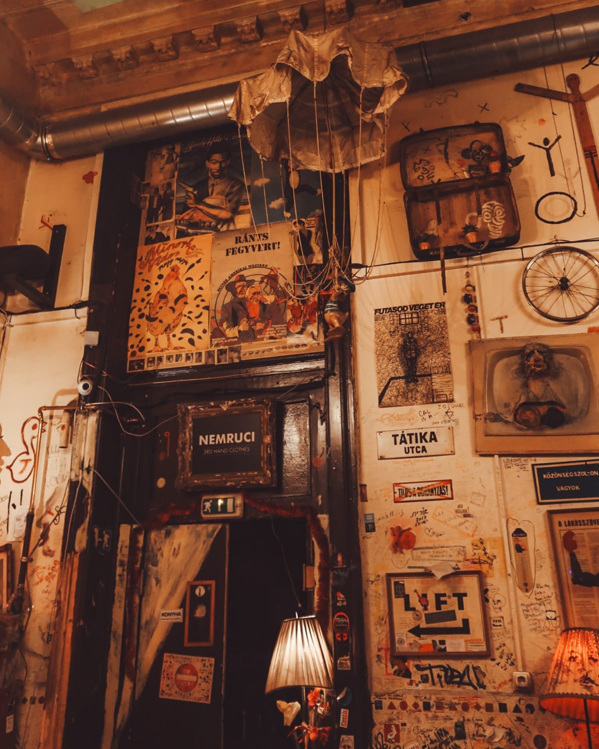 Eclectic interior of a Budapest ruin bar with vintage posters, art, and hanging decorations on graffiti-covered walls.