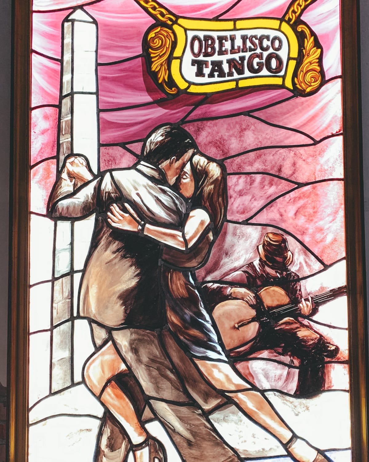 Stained glass of tango dancers and guitarist under "Obelisco Tango" sign in Buenos Aires.