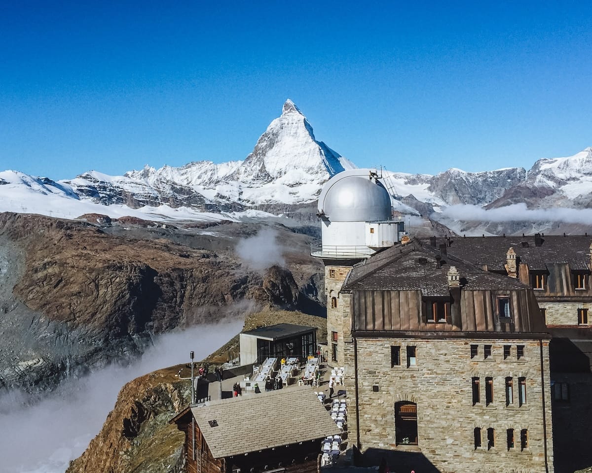 Gornergrat Observatory overlooks a mountain panorama with the Matterhorn towering in the distance above glacier valleys.
