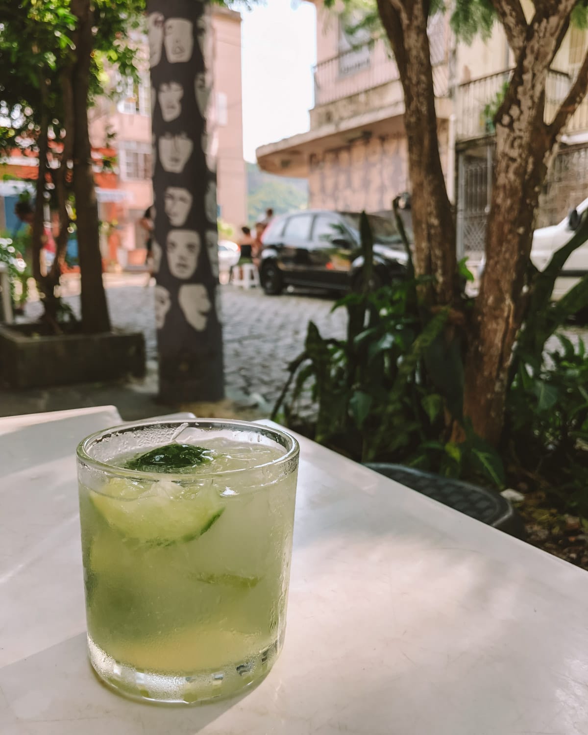 Caipirinha cocktail with lime wedges and mint on a table in a colourful street in Rio de Janeiro.