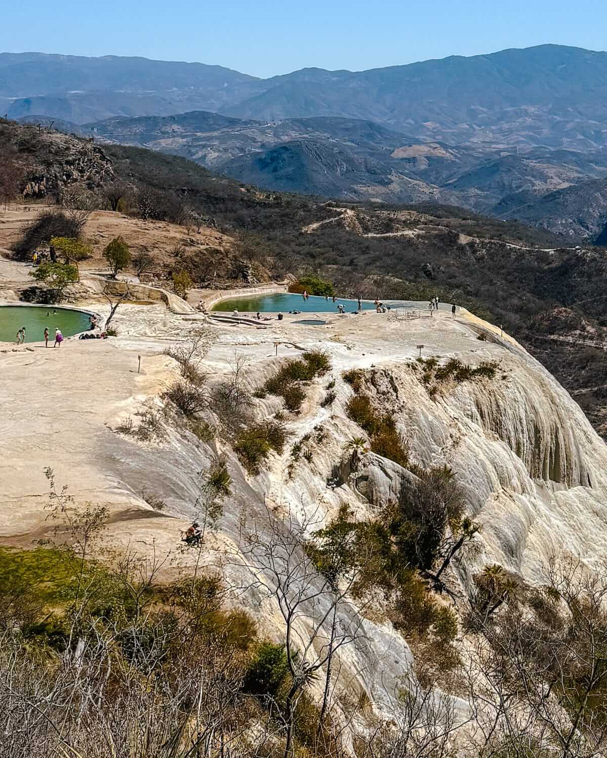 Natural infinity pools at Hierve el Agua sit perched on a petrified rock cliff, overlooking sweeping mountain views in Oaxaca.