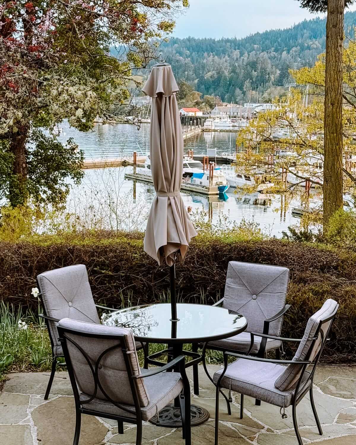 Outdoor table at Hastings House, set with cushioned chairs and overlooking Ganges Harbour marina views.