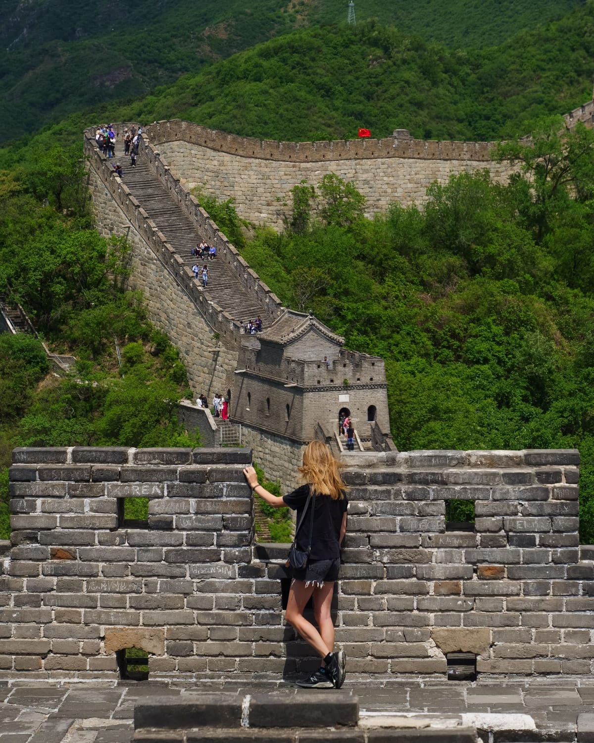 Cec stands at a lookout on the Great Wall of China, gazing at the steep stone steps winding through lush green hills.