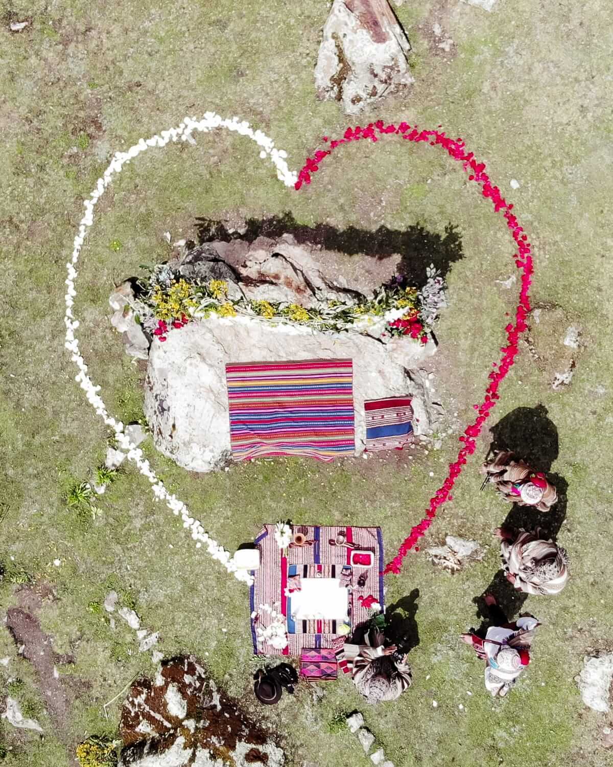 Aerial view of an Andean wedding ceremony in Peru, with floral heart outline and traditional woven blankets.